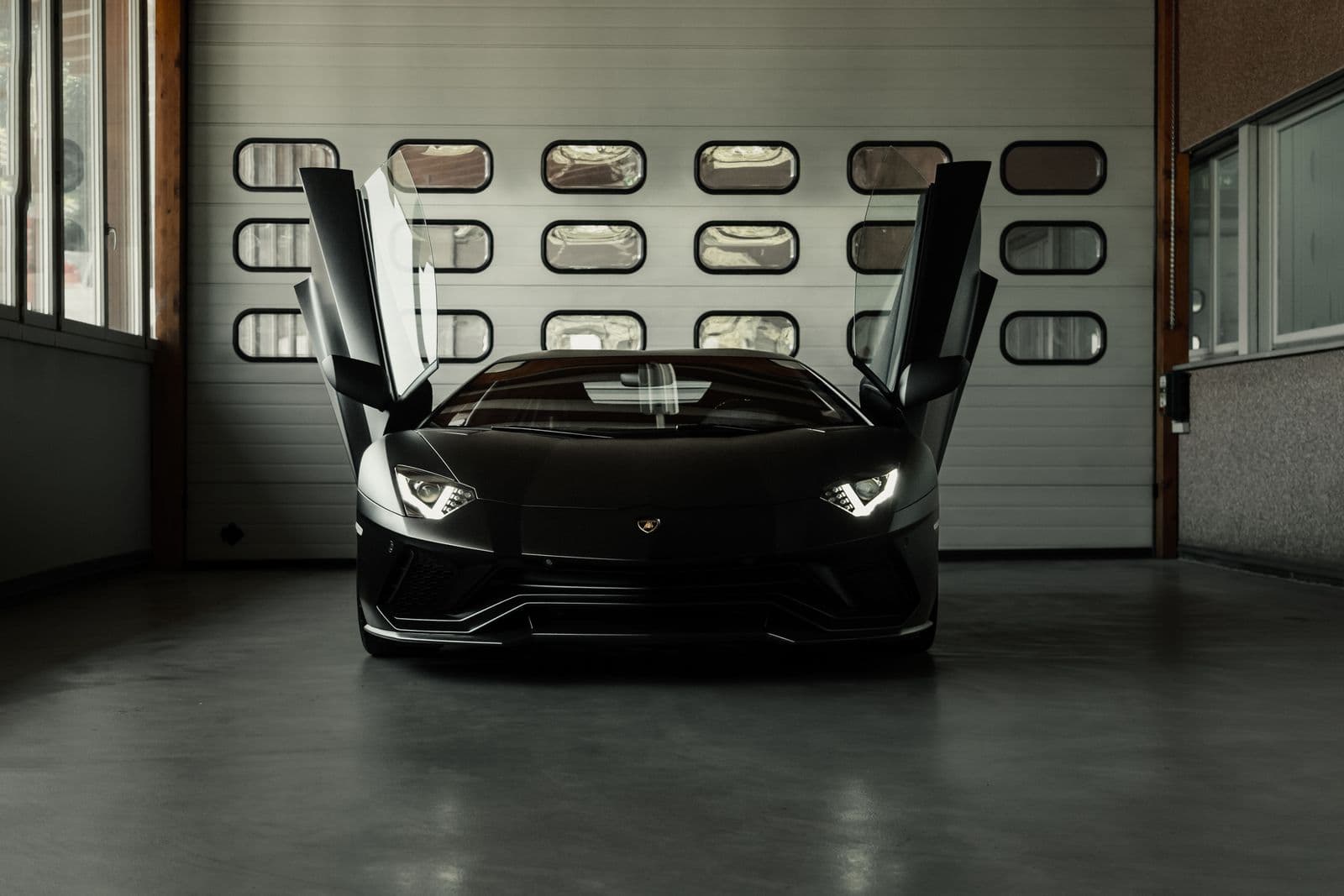 Collector car with doors raised on a smooth dark coated floor inside a private garage — a finish example